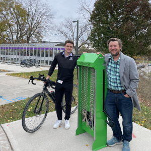 Image of a bike repair station with tools attached to chains and two people standing next to it.